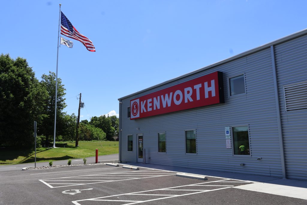 Kenworth of Pennsylvania Lancaster Store Building Exterior With A Large Kenworth Sign and Flag in the Background