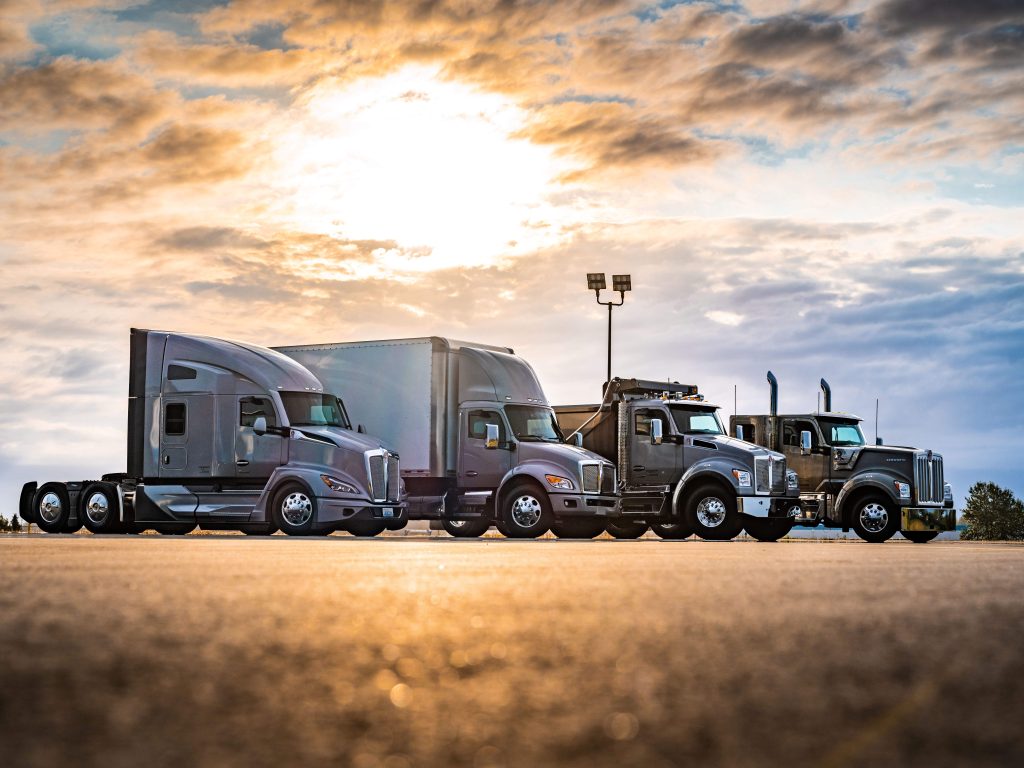 Four Kenworth Trucks With Sun In The Background
