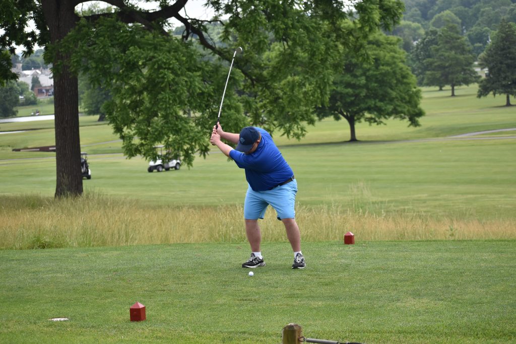 Man swinging to hit a ball on a golf course