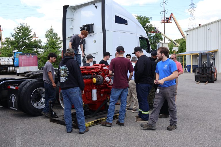Students talking around a Cummins X15 engine